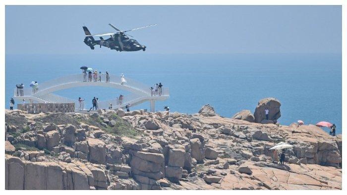 Wisatawan melihat helikopter militer Tiongkok terbang melewati Pulau Pingtan, salah satu wilayah Tiongkok yang paling dekat dengan Taiwan. Tiongkok menggelar latihan militer di sekitar Taiwan mulai 4 Agustus 2022