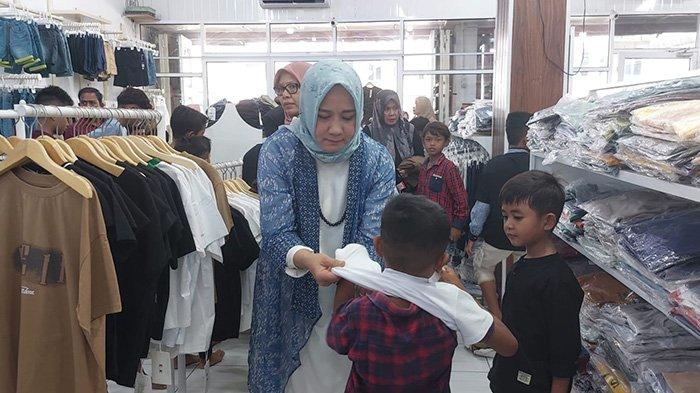 BAJU BARU - Anggota DPD RI, Darwati A Gani memakaikan (tes) baju baru ke si anak saat digelar belanja baju baru untuk anak yatim oleh sahabat duafa di Pidie, Sabtu (22/3/2025).