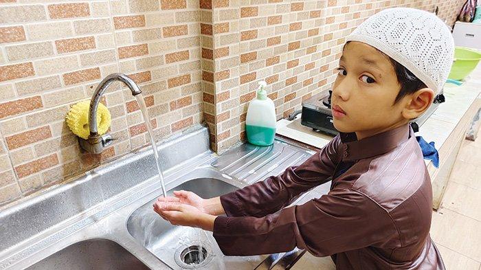 Abdullah Qayyim Harsya (9) sedang mencuci tangan. Keluarga memegang peran kunci dalam menumbuhkan Perilaku Hidup Bersih dan Sehat (PHBS) sejak dini.
