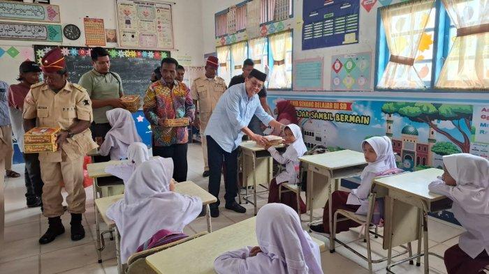 Cabup Pidie, Amiruddin, mengusap kepala murid saat menyerahkan makanan gratis dan bergizi di SD MNS Peureulak, Kecamatan Mutiara, Selasa (19/11/2024).