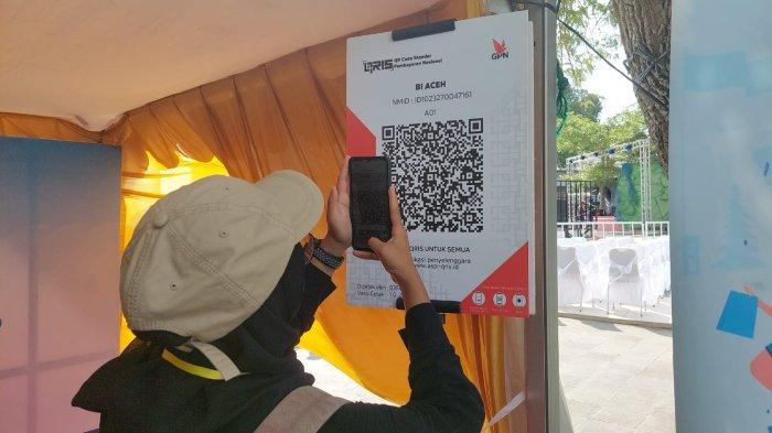 Seorang pengunjung asal Banda Aceh melakukan scan QR pembayaran digital QRIS untuk berbelanja di kawasan Sabang Marine Festival, Jumat (1/3/2024)