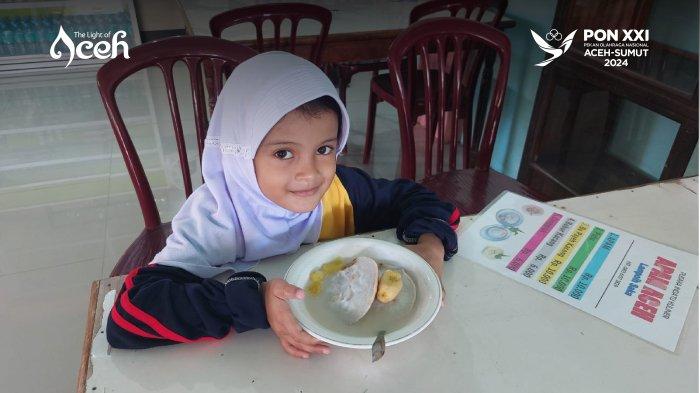 seorang anak sekolah sedang menikmati sajian Apam Aceh di Lamphoih Saka, Pidie yang dijual seharga Rp 10.000 per porsi plus kuah santan.