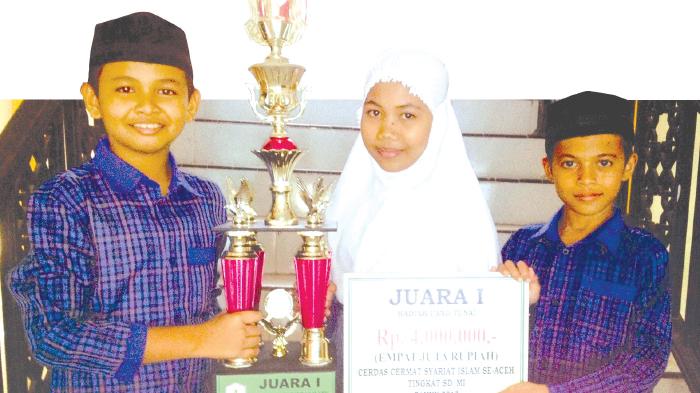 TIGA murid MIN mewakili Kabupaten Bireuen, Haikal Mukarram (kiri), Putri Mulyana, dan Yusran Al Afkar memperlihatkan piala dan hadiah uang Rp 4 juta atas prestasi mereka meraih juara I cerdas cermat syariat Islam tingkat SD/MI se-Aceh di Asrama Haji Banda Aceh, 5-6 Agustus 2015. Foto direkam Kamis (6/8/2015).