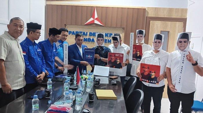 Tim Pemenangan menggenakan baju serba putih dan bertopeng wajah Nahrawi Noerdin saat mendaftarkan pengusaha Aceh itu ke DPD PartaiDemokrat Kota Banda Aceh, Senin (6/5/2024) yang disambut para pengurus partai Demokrat.