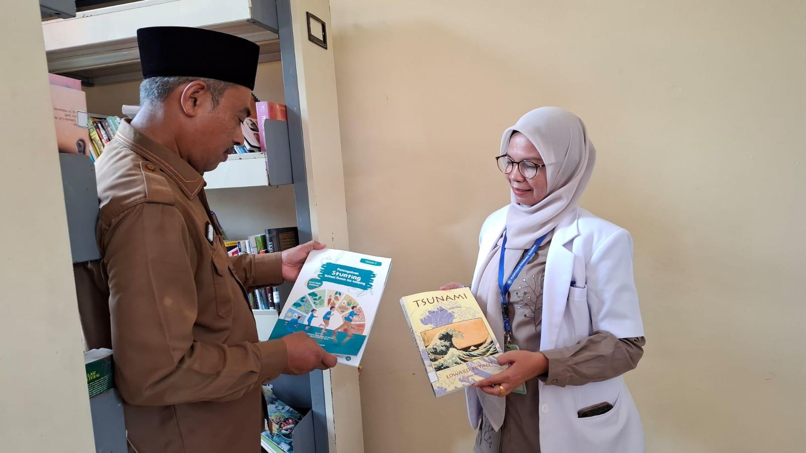 Kepala Dinas Perpustakaan dan Arsip Pidie, Turno Junaidi, memperhatikan buku bacaan di perpustakaan Puskesmas Kembang Tanjong, Selasa (8/7/2025).