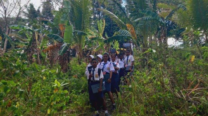 Para siswa dan guru SMP Negeri Satu Atap Mun Kei Besar Kei melintasi hutan untuk mencari signal internet