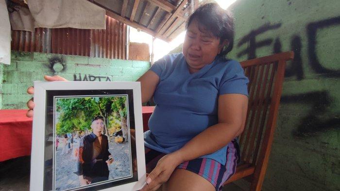 sembari menangis, Putu Suartini menunjukan foto semasa hidup anaknya Adhi Putra Krismawan yang tewas akibat dikeroyok sejumlah pemuda di wilayah Sempidi, Selasa (16/1)