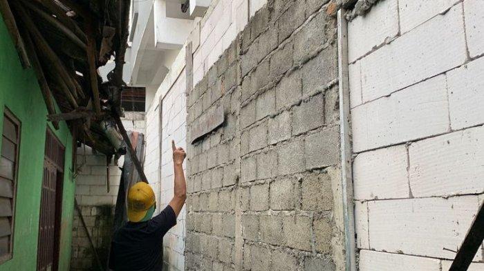 Rumah Ngadenin (63) di Jalan Raya Jatiwaringin, RT 03 RW 04, Kecamatan Pondok Gede, Kota Bekasi, yang akses keluar masuk rumah telah ditutup tembok hotel setinggi 15 meter. Pada Minggu (9/7/2023), Ngadenin menunjukkan tingginya tembok hotel yang menutupi depan, belakang dan samping rumahnya.