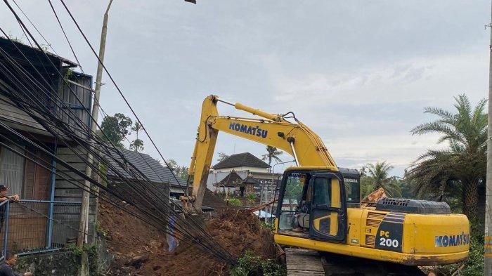 TUMBANG - Terlihat alat berat diturunkan untuk membersihkan tanah akibat pohon beringin yang tumbang di wilayah Darmasaba, Badung pada Minggu 9 Februari 2025.