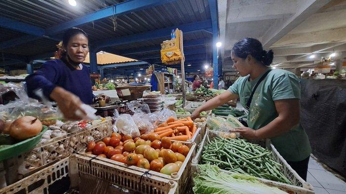 Layani pembeli - Pedagang sayur dan bumbu dapur di Pasar Kidul, Ni Ketut Sutriani, saat melayani pembeli. Diketahui harga tomat hingga bulan Mei masih tergolong tinggi. Sedangkan harga cabai rawit merah turun drastis, yakni di harga Rp 30 ribu per kilo.