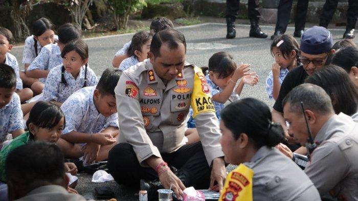 MAKAN GRATIS - Kapolres Klungkung AKBP Alfons W P Letsoin duduk lesehan bersama anak-anak saat giat membagikan makanan bergizi gratis kepada siswa di SD Negeri 3 Tihingan, Kecamatan Banjarangkan, Kabupaten Klungkung, Rabu (13/11). Program makan bergizi gratis ini merupakan kegiatan untuk mendukung program Asta Cita, Presiden Prabowo Subianto.