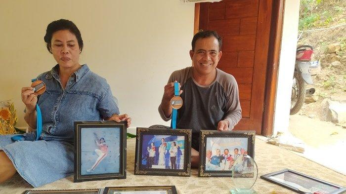 I Dewa Putu Sekar (kiri) bersama istrinya menunjukan sejumlah medali yang diraih oleh Desak Rita selama menjadi atlet panjat tebing, Kamis (4/10).