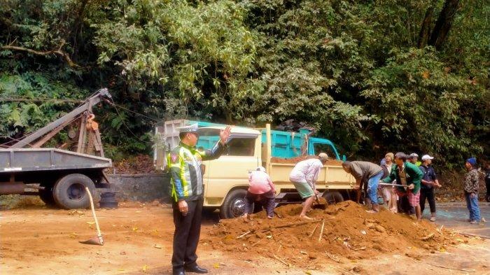 Polisi saat berjibaku membersihkan tanah yang tumpah akibat kecelakaan tunggal yang dialami truk DK 9362 PE di jalur Singaraja-Denpasar tepatnya di Desa Pancasari, Kecamatan Sukasada, Buleleng, Kamis (28/9).