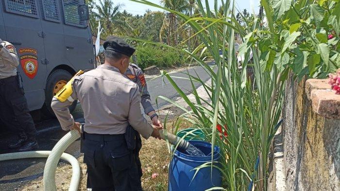AIR BERSIH - Penyaluran air bersih dari Satuan Samapta Polres Jembrana kepada warga Banjar Benel, Desa Manistutu, Kecamatan Melaya, Jembrana, Senin (30/10).