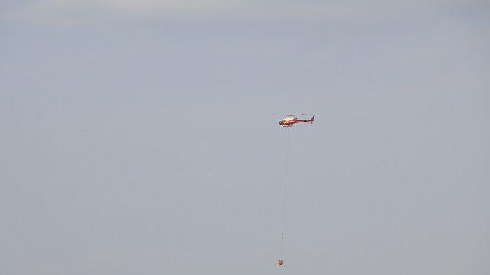 Helikopter jenis AS350B3 milik BNPB tengah melakukan proses pemadaman kebakaran di TPA Suwung Denpasar dengan menggunakan metode water bombing, Jumat 13 Oktober 2023.