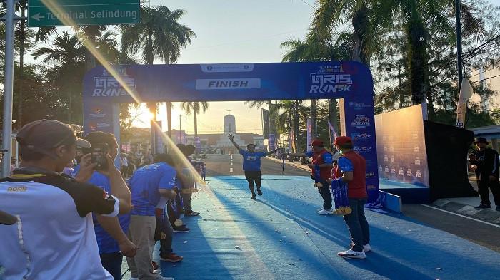 GARIS FINIS -- Salah satu pelari melintasi garis finis pada ajang QRIS Run 5K di Alun-Alun Taman Merdeka Pangkalpinang, Minggu (27/7/2025).