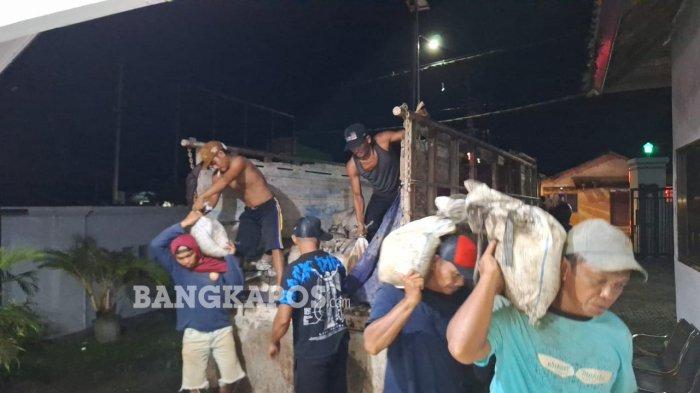 ANGKUT TIMAH ILEGAL - Pekerja membawa pasir timah ilegal dari truk dan ke Pos TNI AL Babel, Pangkalbalam, Kota Pangkalpinang, Jumat (13/6/2025). Timah ilegal sebanyak 914 karung atau sekitar 45,7 ton yang belum diketahui pemiliknya itu diangkut dari KM Indah Jaya.