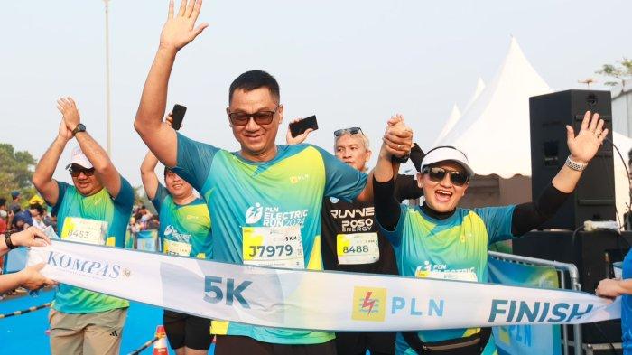 Direktur Utama PLN, Darmawan Prasodjo (kiri) bersama istri, Diny Darmawan Prasodjo (kanan) saat melintasi garis finish dan menyelesaikan PLN Electric Run 2024 kategori 5K.