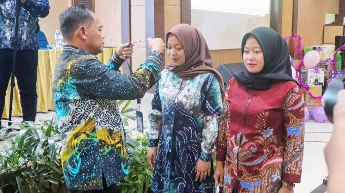 Kepala Dinas Pemberdayaan Masyarakat dan Desa Kabupaten Tanah Bumbu, Samsir, mengalungkan tanda pengenal pada peserta Bimbingan Teknis Pelaksanaan Posyandu untuk Percepatan Penanganan Stunting, 3 sampai 5 November 2023.