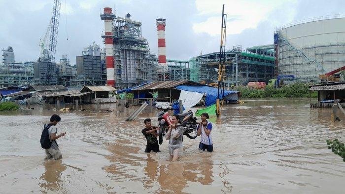 Warga mengevakuasi sepeda motor yang terparkir di area parkir Kawasan Proyek Pabrik PT Lotte Chemical, Sabtu (3/2/2024). Ratusan sepeda motor tergenang banjir di area parkir.