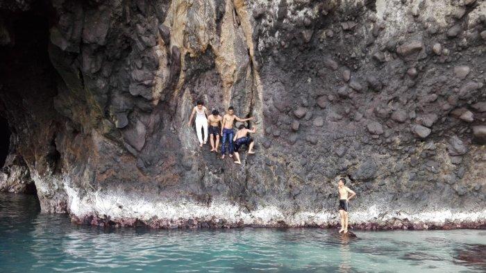 Wisatawan lompat dari atas tebing ke kolam air laut di Goa Kelelawar yang berada di Pulau Shangiang, Selat sunda, Kabupaten Serang, Banten.