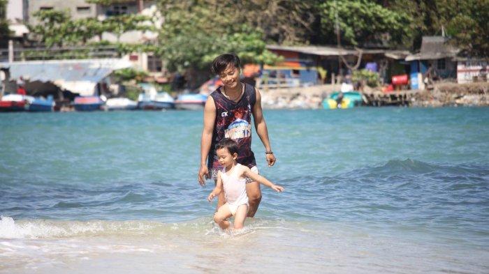Wisatawan saat sedang main dengan anaknya di Pulau Merak Kecil.