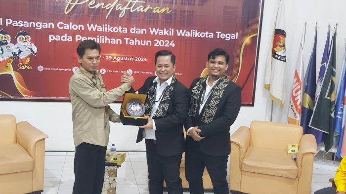 Calon Wali Kota dan Wakil Wali Kota Tegal, Faruq Ibnul Haqi (tengah) dan Muhammad Ashim Adz Dzorif Fikri (kanan) saat menerima cinderamata dari KPU Kota Tegal, Kamis (29/8/2024). Faruq dan Ashim sebagai pasangan termuda resmi mendaftar untuk maju pada Pilkada Kota Tegal.