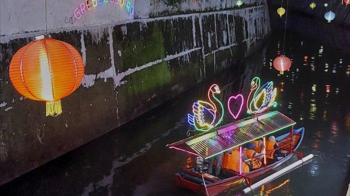 Pengunjung menaiki perahu wisata menyusuri Kali Pepe di Kota Solo, Jumat (24/1/2025) petang.