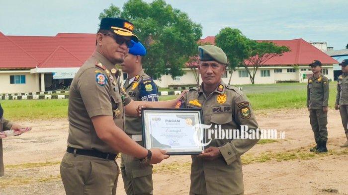 SATPOL PP LINGGA VIRAL - Erwansyah, anggota Satpol PP Kabupaten Lingga, Provinsi Kepulauan Riau, saat menerima penghargaan dari pimpinannya, Dody Suhendra, Senin (19/5/2025).