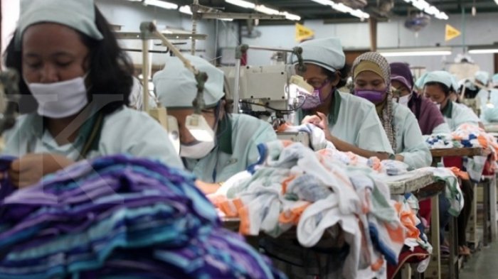PEKERJA GARMEN - Para pekerja perusahaan garmen sedang menjahit pakaian.