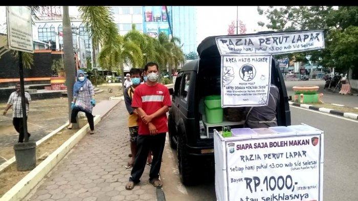 RAZIA PERUT LAPAR - Warga antre untuk mendapat makanan Razia Perut Lapar Bripka Zulhamsyah, di kawasan Pelabuhan Sri Bintan Pura Tanjungpinang, Jumat (19/2/2021).