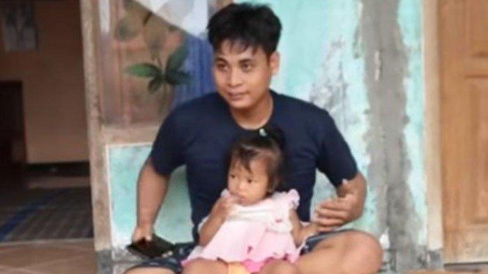 Ponari bersama anaknya sedang duduk di depan rumah, di Jombang, Jawa Timur.