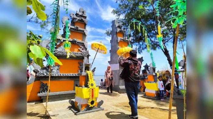 Wisatawan berfoto di gapura mirip di Bali saat berwisata di Pantai Tirta Ayu Indramayu di Desa/Kecamatan Balongan, Kabupaten Indramayu, Minggu (18/12/2022).