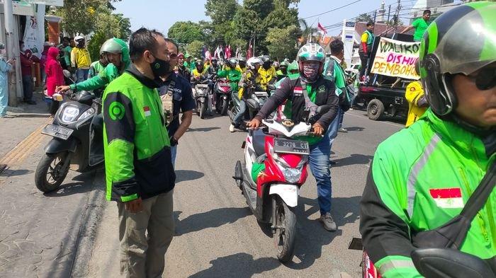 Ratusan pengemudi ojek online (ojol) melakukan aksi unjuk rasa menagih janji pemerintah untuk memberikan anggaran Bantuan Langsung Tunai (BLT) di tahun 2022./ Dalam aksinya, para ojol melakukan long march sambil mendorong motor mereka hingga ke depan Balaikota Cirebon, Rabu (9/8/2023).
