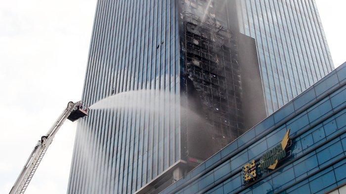 Pemadam kebakaran melakukan pendinginan pada bagian gedung K-Link Tower yang terbakar di Jakarta, Sabtu (15/7/2023). Kebakaran tersebut menyebabkan dua orang korban menderita luka bakar dan segera dilarikan ke rumah sakit.