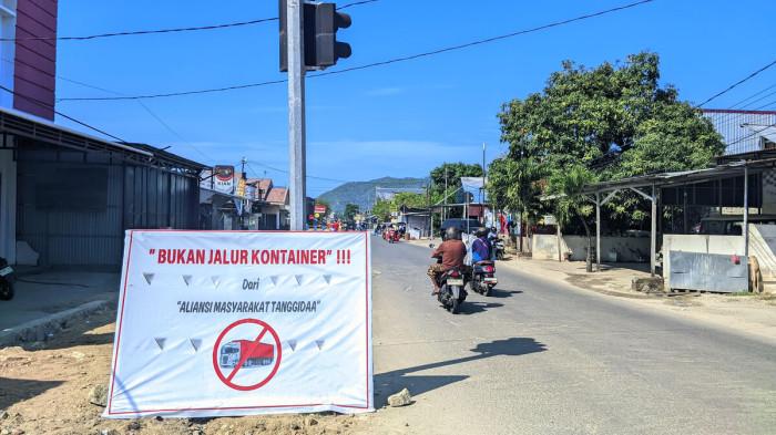 LALU LINTAS -- Baliho di Jalan HOS Cokroaminoto, Kota Gorontalo, Senin (28/7/2025). Warga protes terhadap truk kontener yang lalu lalang di Jalan HOS Cokroaminoto.