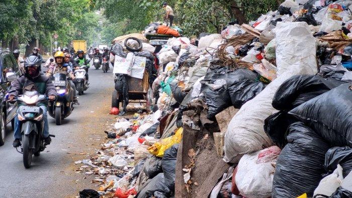 Pengguna jalan melintasi tumpukan sampah yang menggunung di Tempat Pembuangan Sementara (TPS) tegallega, Jalan Moch. Toha, Kota Bandung, Jawa Barat, Kamis (12/10/2023).