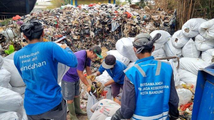 Sejumlah petugas memasukan sampah yang sudah digibrik ke dalam karung di sekitar tumpukan sampah yang menggunung di Tempat Pembuangan Sementara (TPS) tegallega, Jalan Moch. Toha, Kota Bandung, Jawa Barat, Kamis (12/10/2023).