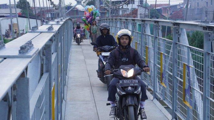 Kendaraan sepeda motor melintas di jembatan gantung yang melintang di Sungai Citarum, Desa Rancamanyar, Kecamatan Baleendah, Kabupaten Bandung, Jawa Barat, Senin (12/2/2024).