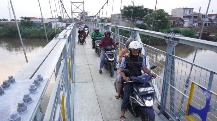 Kendaraan sepeda motor melintas di jembatan gantung yang melintang di Sungai Citarum, Desa Rancamanyar, Kecamatan Baleendah, Kabupaten Bandung, Jawa Barat, Senin (12/2/2024).
