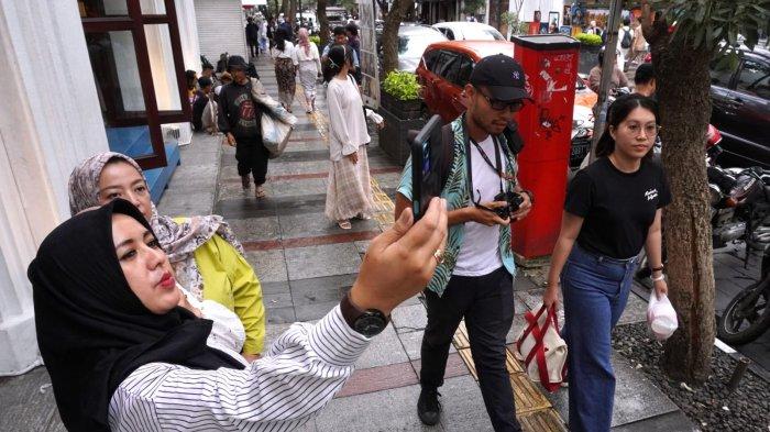 Wisatawan mengisi waktu sore di Jalan Braga, Kota Bandung, Jawa Barat, Sabtu (20/4/2024).