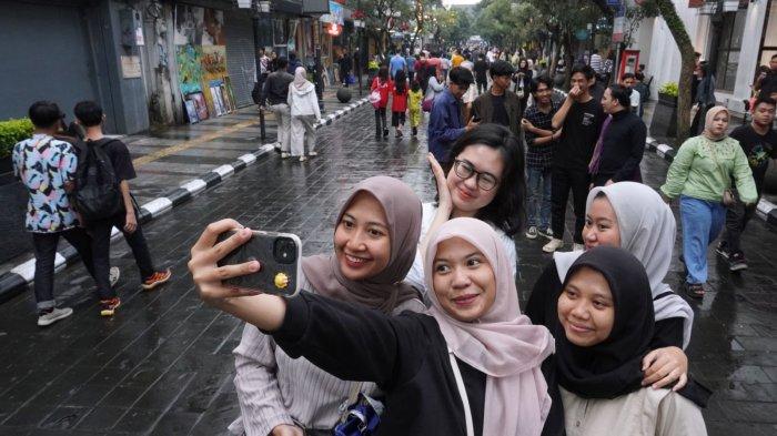 Wisatawan berswafoto saat jalan-jalan sore bebas kendaraan (Braga Free Vehicle) di Jalan Braga, Kota Bandung, Jawa Barat, Sabtu (18/5/2024).