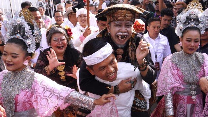 Bakal calon gubernur Jawa Barat, Dedi Mulyadi yang berpasangan dengan bakal calon wakilnya, Erwan Setiawan menggendong kakek Lengser Sunda saat penyambutan untuk pendaftaran Pilgub Jabar 2024 di Kantor KPU Jawa Barat, Jalan Garut, Kota Bandung, Selasa (27/8/2024) sore.