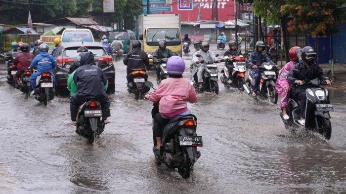 Pemotor berangkat kerja menggunakan jas hujan di saat hujan rintik-rintik, melintas di Jalan Raya Dayeuhkolot, Kecamatan Dayeuhkolot, Kabupaten Bandung, Jawa Barat, Rabu (4/12/2024).