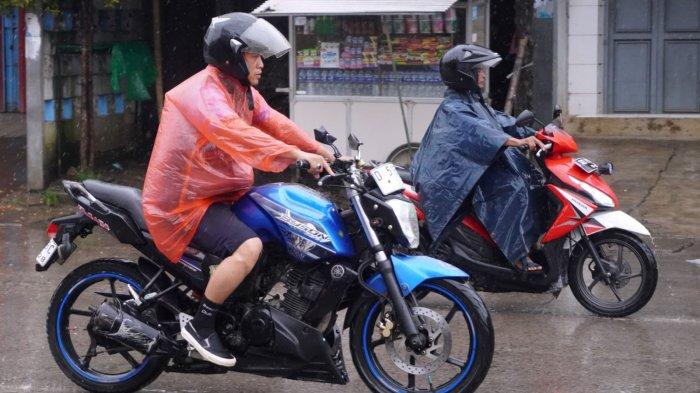 Pemotor berangkat kerja menggunakan jas hujan di saat hujan rintik-rintik, melintas di Jalan Raya Dayeuhkolot, Kecamatan Dayeuhkolot, Kabupaten Bandung, Jawa Barat, Rabu (4/12/2024).