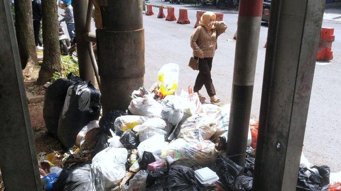 Pengguna jalan melintasi sampah yang menumpuk di pinggir jalan depan Rumah Sakit Hasan Sadikin (RSHS), Jalan Pasirkaliki, Kota Bandung, Jawa Barat, Selasa (7/1/2025).