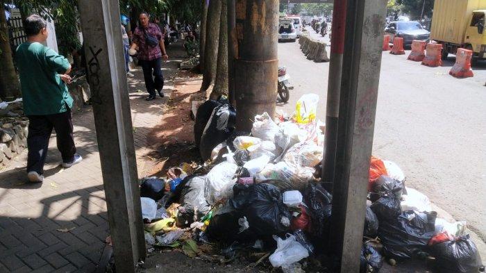 Pengguna jalan melintasi sampah yang menumpuk di pinggir jalan depan Rumah Sakit Hasan Sadikin (RSHS), Jalan Pasirkaliki, Kota Bandung, Jawa Barat, Selasa (7/1/2025).