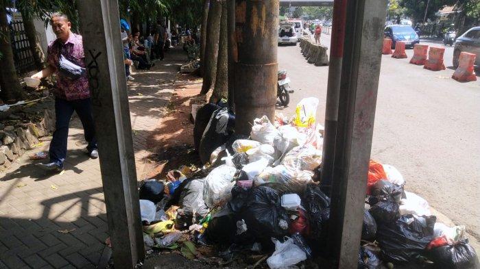 Pengguna jalan melintasi sampah yang menumpuk di pinggir jalan depan Rumah Sakit Hasan Sadikin (RSHS), Jalan Pasirkaliki, Kota Bandung, Jawa Barat, Selasa (7/1/2025).