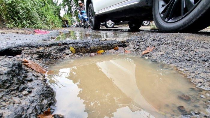 Pengguna jalan melintasi jalan rusak berlubang dan bak kontrol yang mengeluarkan air di Jalan Tera, Kelurahan Braga, Kecamatan Sumur Bandung, Kota Bandung, Jawa Barat, Jumat (7/2/2025).