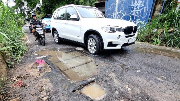 Pengguna jalan melintasi jalan rusak berlubang dan bak kontrol yang mengeluarkan air di Jalan Tera, Kelurahan Braga, Kecamatan Sumur Bandung, Kota Bandung, Jawa Barat, Jumat (7/2/2025).